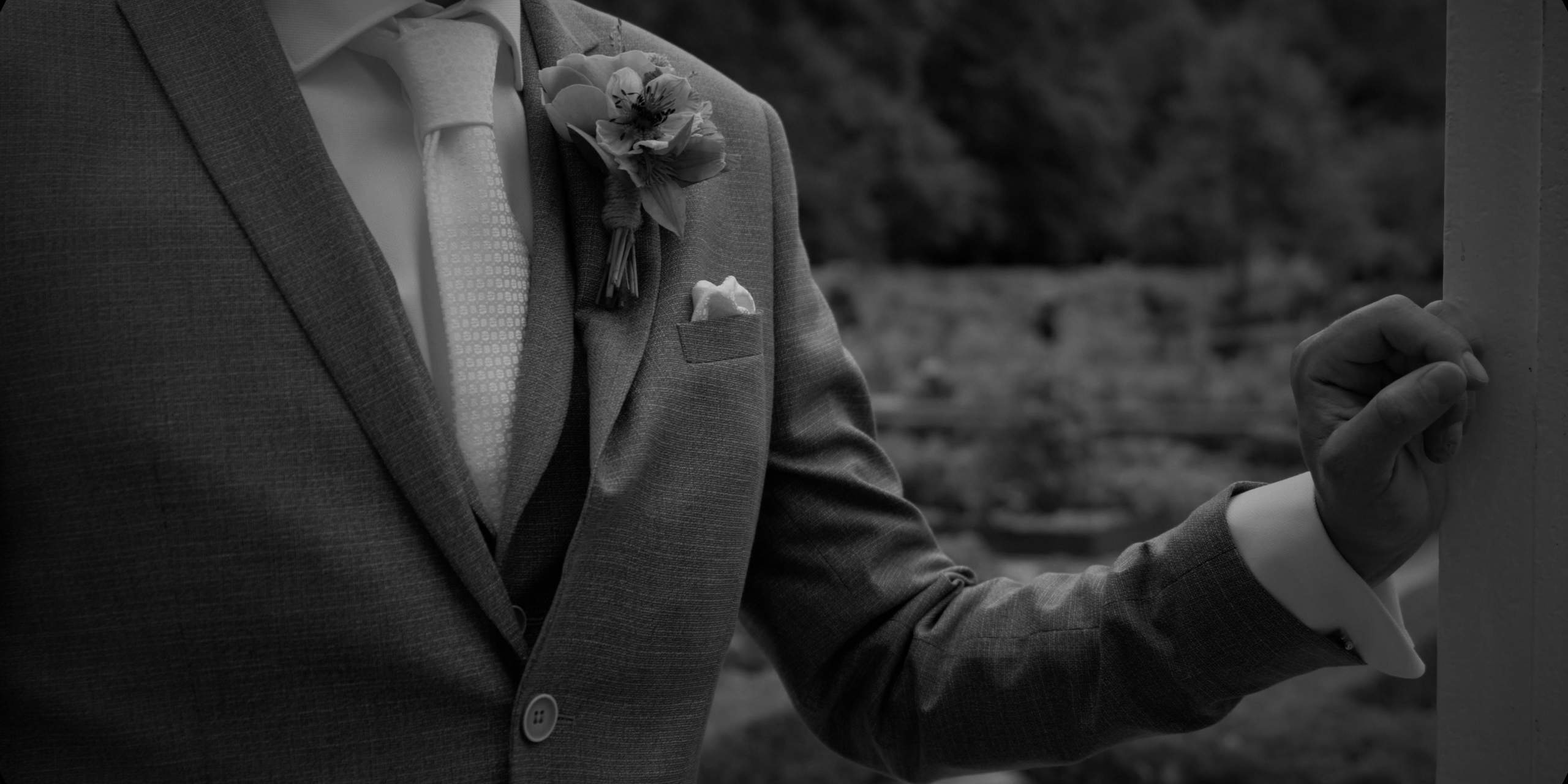 Detail van het pak van bruidegom Mark met corsage, zwart-wit