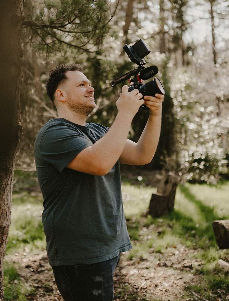 Bruidsvideograaf Justin van Wijnen lachend aan het filmen met zijn camera in het bos