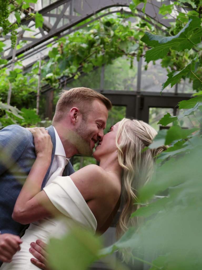 Barry en Chantal kussen elkaar tussen het groen bij de kas