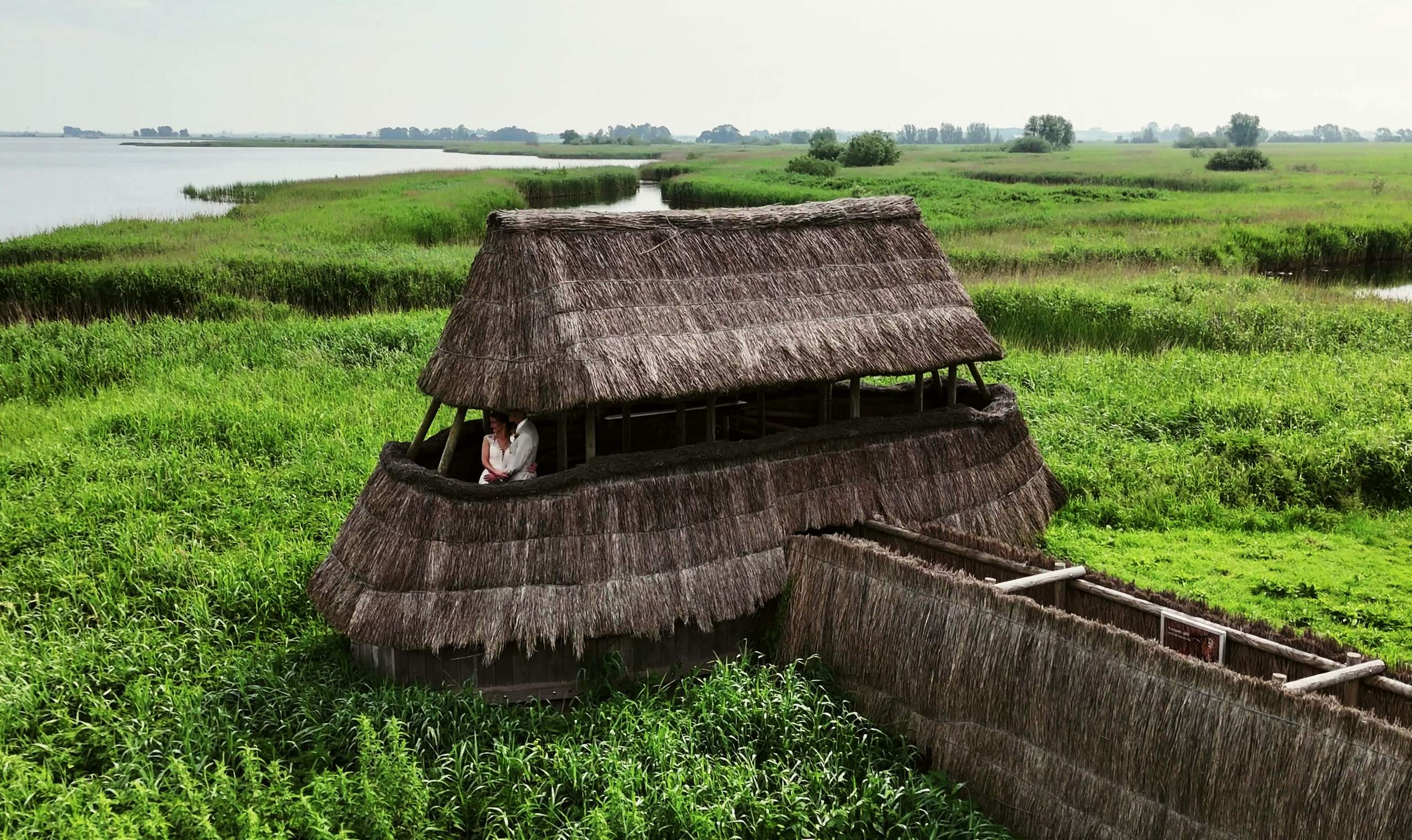 Dronebeeld van een rieten vogelkijkhut in het groene rietland aan het water