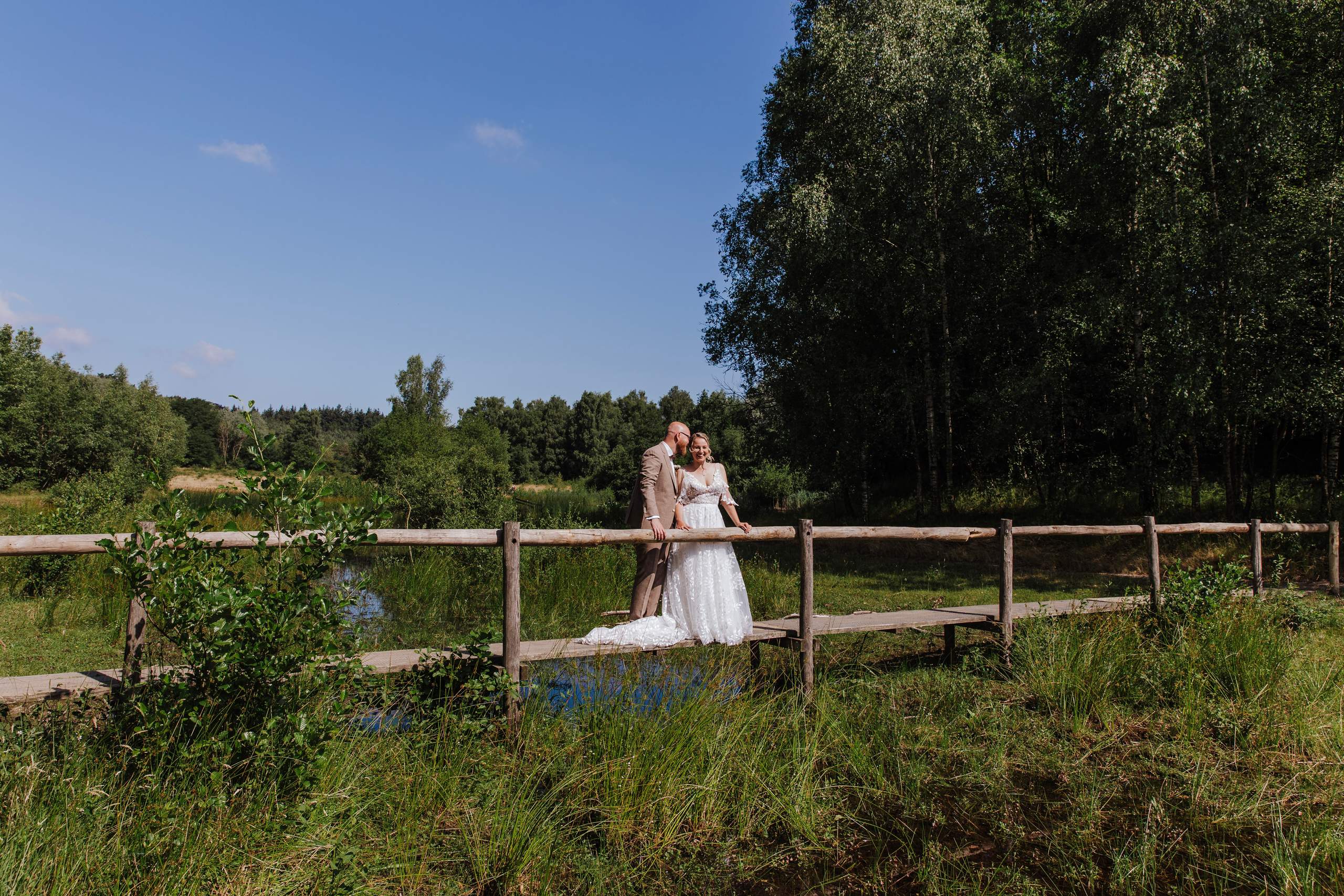 Gerwin en Elena op een houten brug in het groen op hun trouwdag