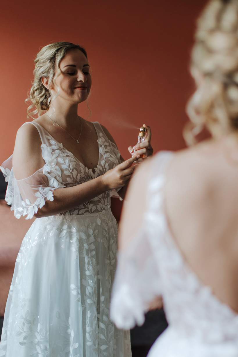 Bruid Elena spuit parfum op tijdens de voorbereidingen van haar trouwdag
