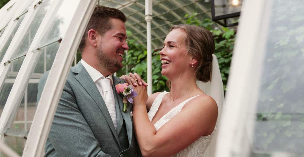 Mark en Sanne lachen elkaar toe in de kas van De Havixhorst in Meppel op hun trouwdag